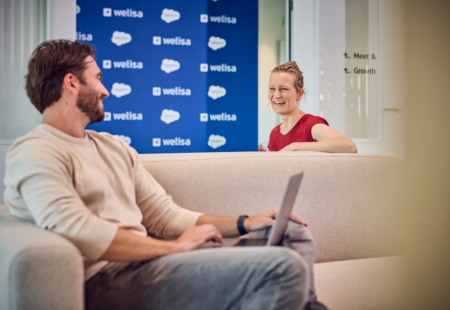 Medewerkers op de bank met op de achtergrond een banner met salesforce logo's