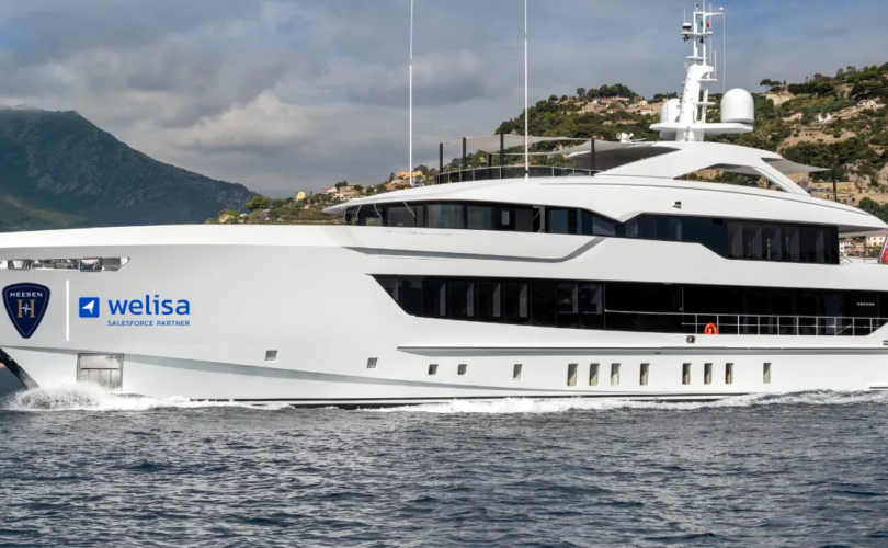 Een groot wit luxe superjacht van Heesen Yachts varend op het water, met de logo's van Heesen Yachts en Welisa Salesforce Partner.