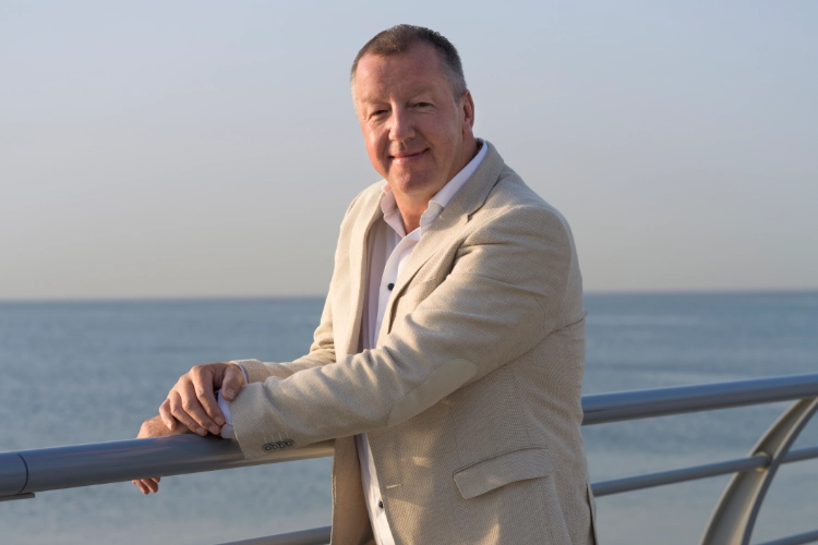 Jeroen van de Meer staat tegen de railing op een jacht op het water